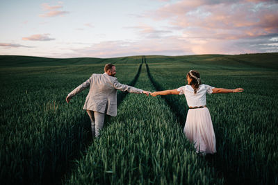 Full length of friends standing on field against sky