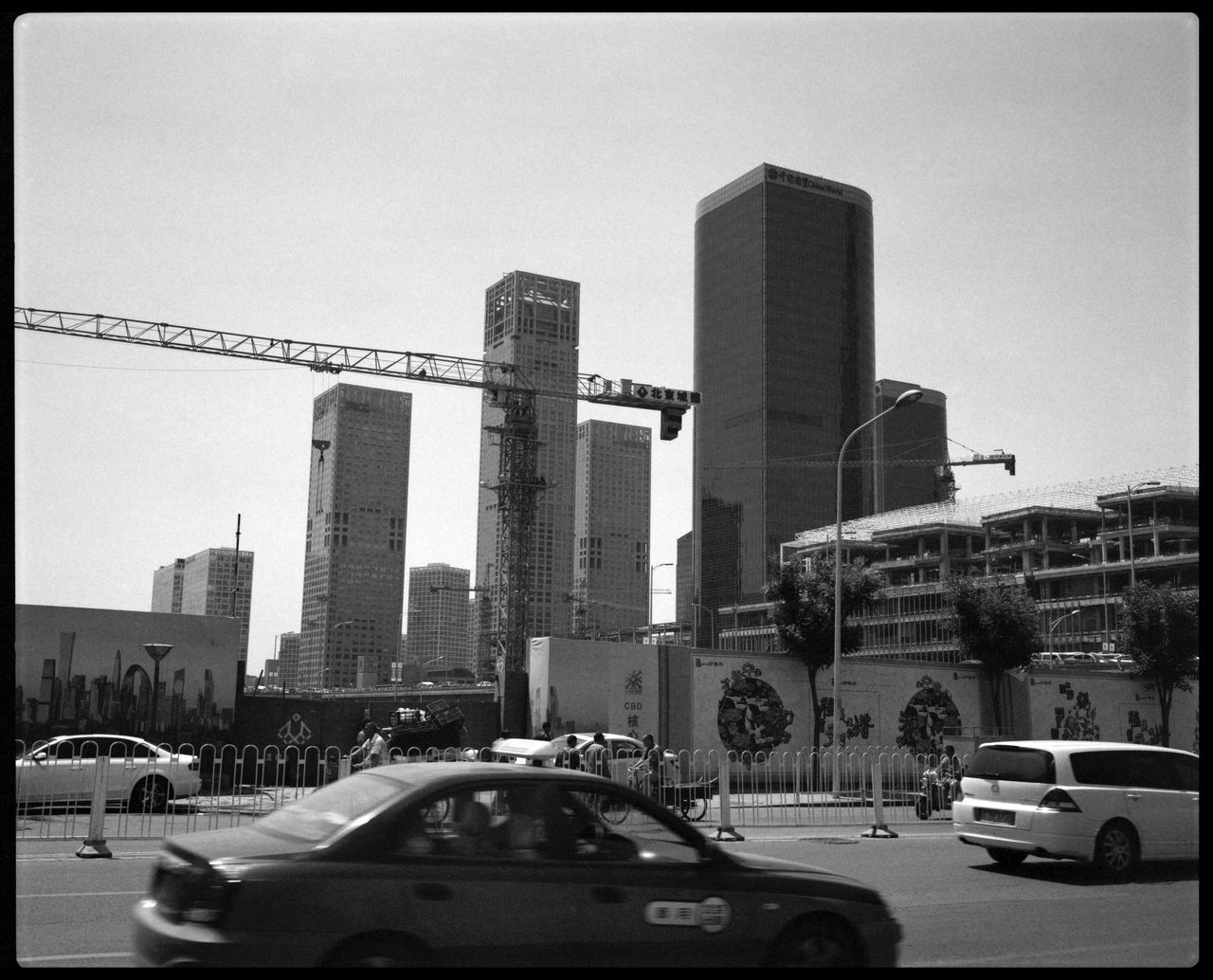 TRAFFIC ON ROAD BY BUILDINGS AGAINST SKY