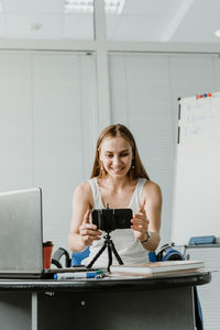 Young woman blogging over smart phone at home