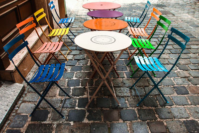 High angle view of colorful empty seat and table arranged at sidewalk cafe