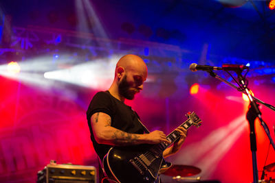 Man playing guitar at illuminated music concert
