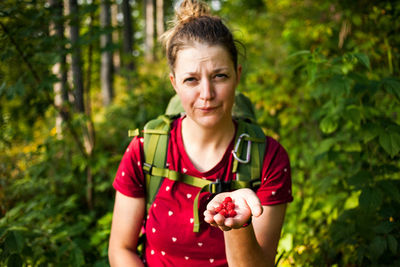 Portrait of smiling woman holding apple against trees