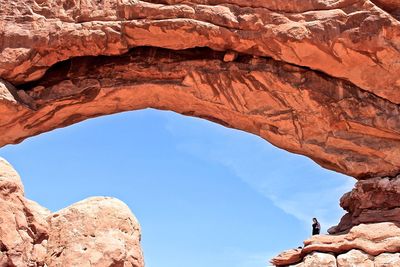 Low angle view of woman below natural arch at arches national park