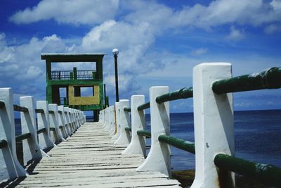 Pier on sea against cloudy sky