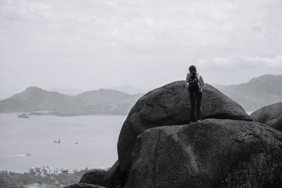 Man on rock by sea against sky