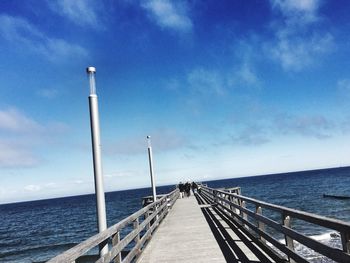 People walking on pier over baltic sea