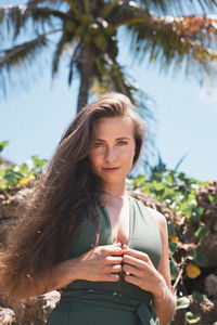 Portrait of young woman in front of palm tree