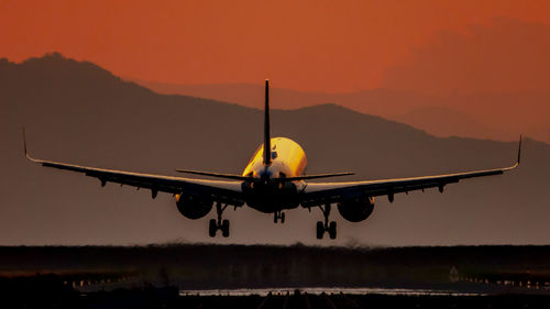 Airplane flying in sky during sunset