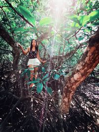 Woman standing by tree trunk in forest