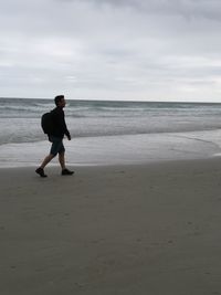 Full length of man standing on beach against sky