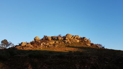 Low angle view of rock formation against clear blue sky