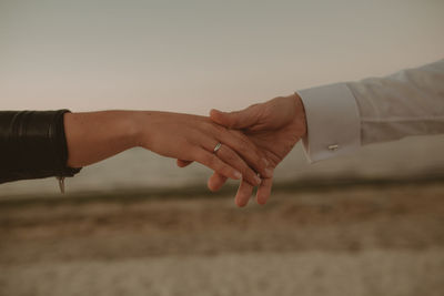 Midsection of couple holding hands