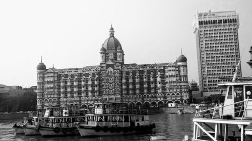 View of boats moored in city against clear sky
