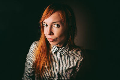 Portrait of woman with long hair against black background