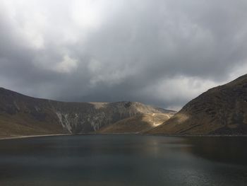 Scenic view of lake and mountains against cloudy sky
