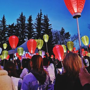 Rear view of people with balloons against sky