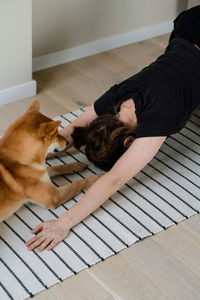 Millennial women training with her domestic dog positions dog face down