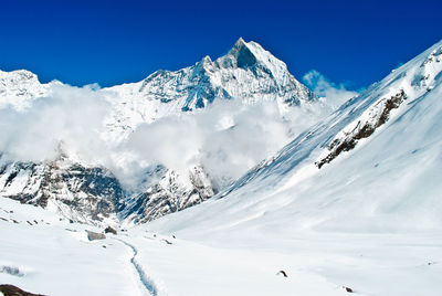 Scenic view of snow covered mountains against blue sky