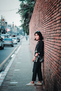 Side view of young woman standing against wall