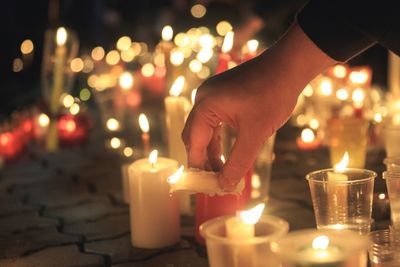 Close-up of hand holding lit candles