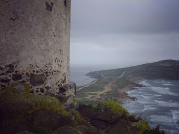 Scenic view of sea by mountains against sky