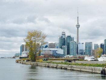 City at waterfront against cloudy sky