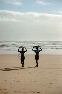 Rear view of woman walking at beach surfing 