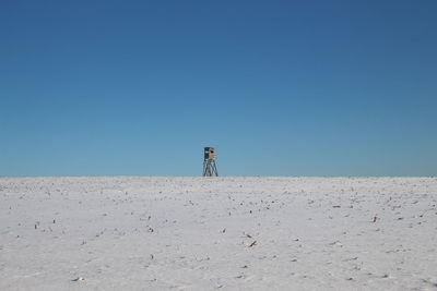 Man standing on sand at beach against clear blue sky