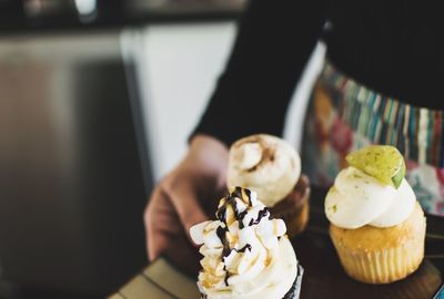 Cropped image of woman holding cup cakes in plate