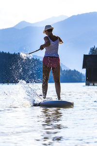 Rear view of woman paddleboarding in lake