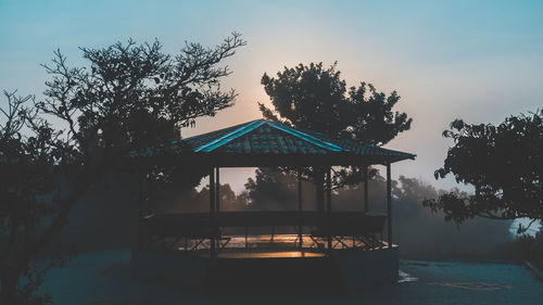 Silhouette trees by swimming pool against sky during sunset