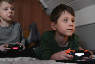 Kids playing video games at home on the bed at night. boys using game console and having fun in the