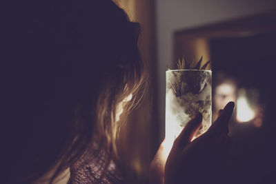 Reflection of woman holding pineapple drink in glass 