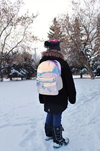 Rear view of woman standing on snow covered field