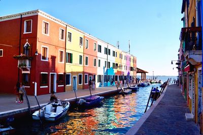 Boats moored in canal against buildings in city