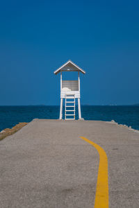 Lifeguard hut on beach against clear blue sky