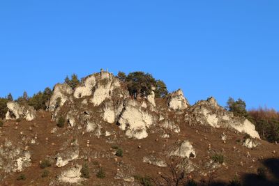 Low angle view of rock formations against clear blue sky