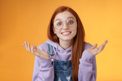 Portrait of smiling woman standing against orange background