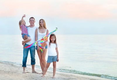 Happy family standing at beach near seashore