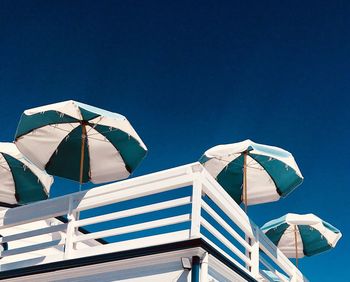 Low angle view of parasol against clear blue sky