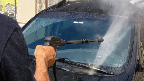 Man spraying water on car windshield