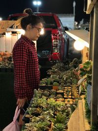 Side view of woman looking at succulent plants for sale in market stall