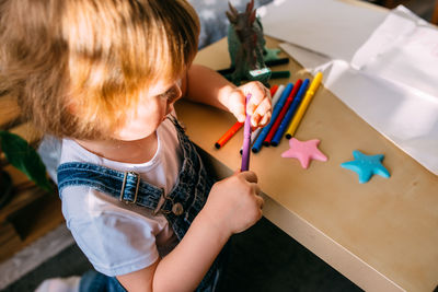 High angle view of girl drawing on paper