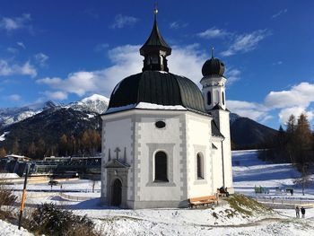 Church by building against sky during winter