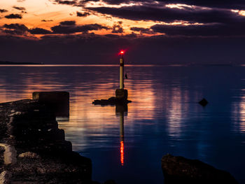 Silhouette man by sea against sky during sunset