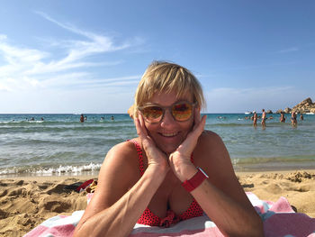 Portrait of smiling young woman on beach against sky