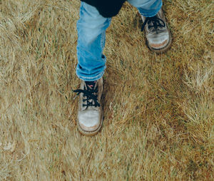 Low section of child in boots standing on field