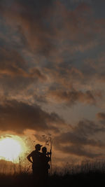 Silhouette man standing on field against sky during sunset