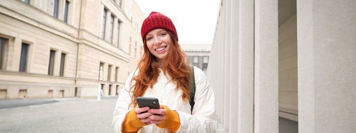 Portrait of young woman standing in city