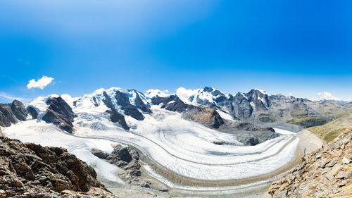 Scenic view of snowcapped mountains against blue sky